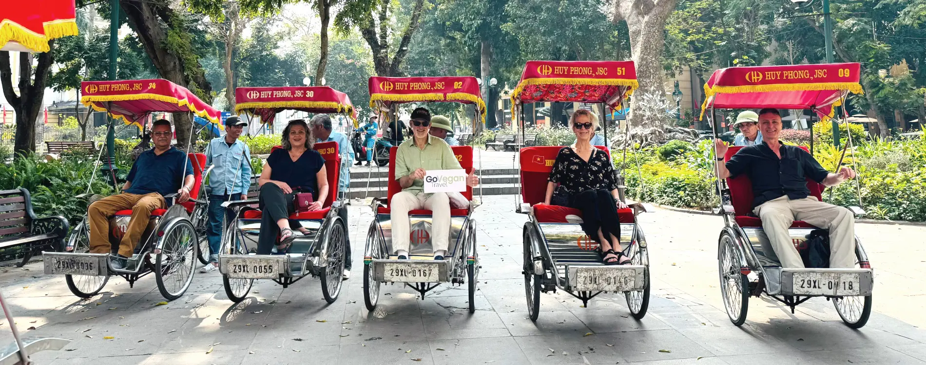 Martin and four GoVegan Travel guests riding cyclos beside Hoan Kiem Lake on a small group vegan tour in Vietnam