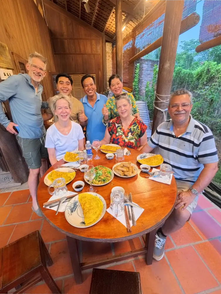 GoVegan Travel guests and Mekong Delta homestay hosts sharing a vegan dinner on a small group vegan tour in Vietnam